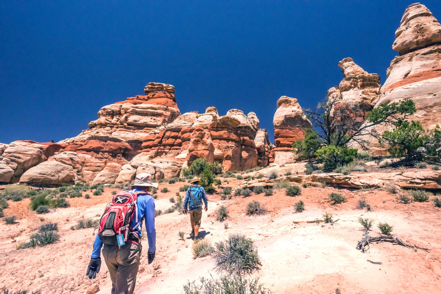 Two hikers make their way up a somewhat steep incline on their way to the Doll House in Canyonlands National Park.
