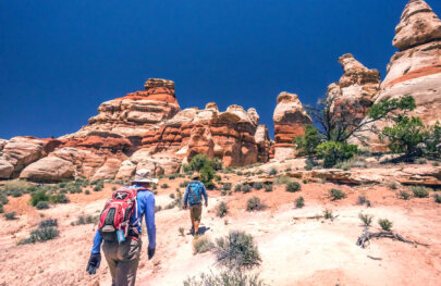 Two hikers make their way up a somewhat steep incline on their way to the Doll House in Canyonlands National Park.