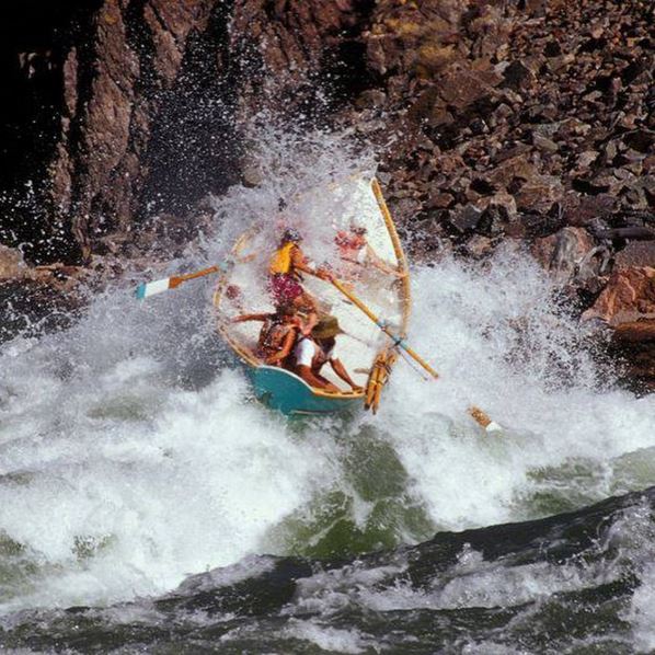 A dory goes up on it's side almost verticcal in a giant whitewater wave on the Colorado River in Grand Cnayon.
