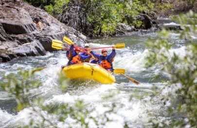 A group celebrates after rafting through a rapid on the Merced River