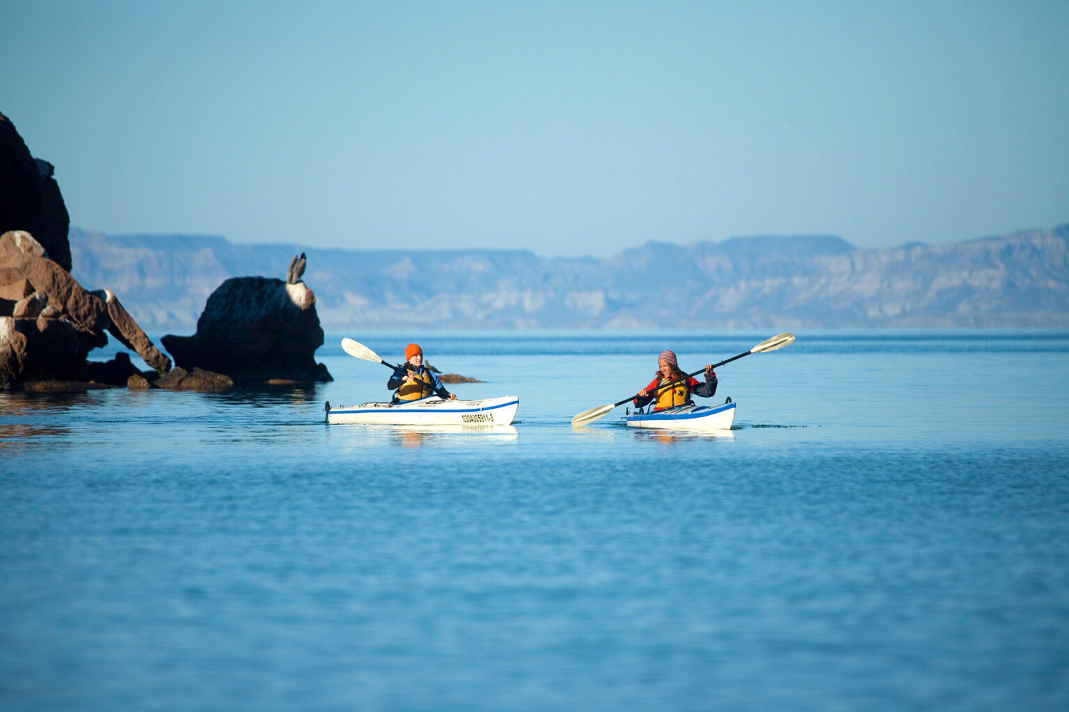 Two kayakers paddle on the ocean in Baja Mexico.