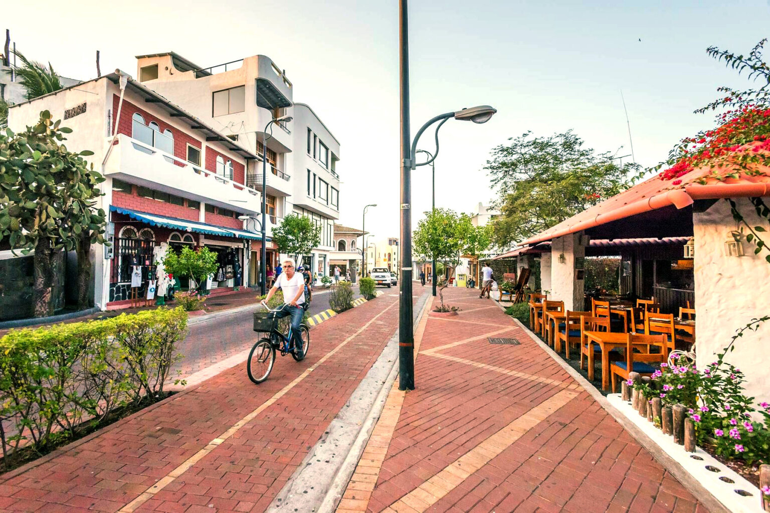 A man rides a bike down the sidewalk in the city.
