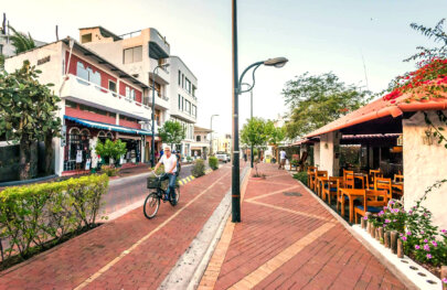 A man rides a bike down the sidewalk in the city.