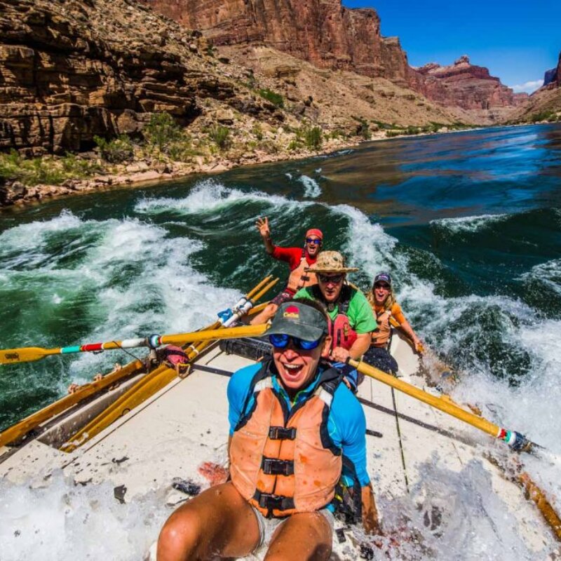 Guests beam with excitement as they go through a rapid in Grand Canyon in a dory.