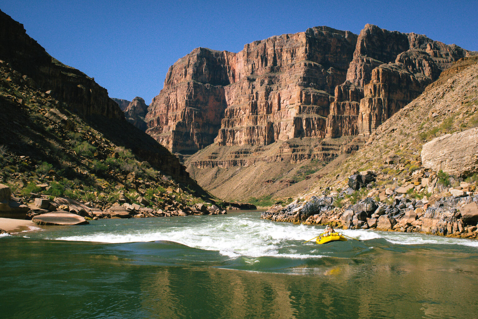 OARS raft navigates Class III rapid in lower section of Grand Canyon