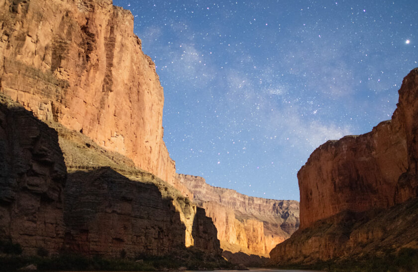 Illuminated tent pitched next to the Colorado River in Grand Canyon