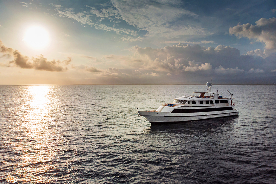 The Integrity yacht sailing on the sea as the sun starts to set above the horizon.
