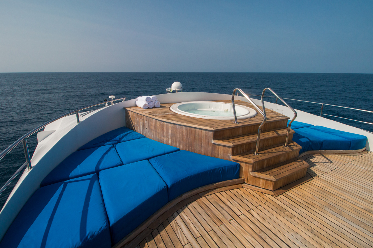 Large blue cushion suround a raised spa on the sun deck of the Integrity yacht.