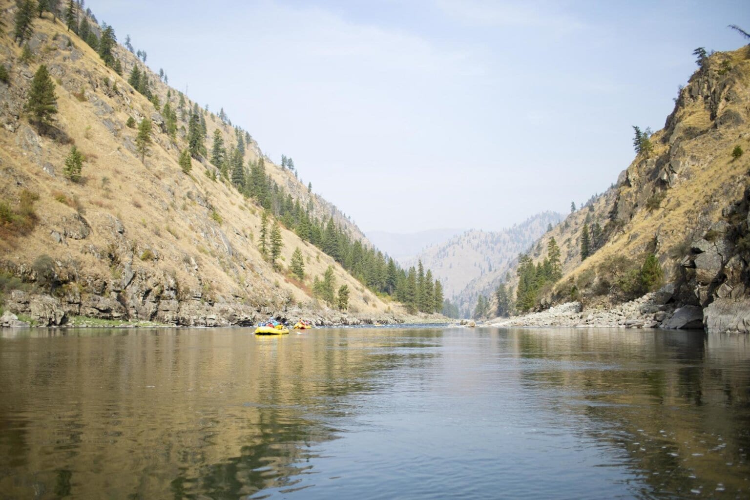 A yellow OARS raft floats on a calm stretch of the Main Salmon River in Idaho