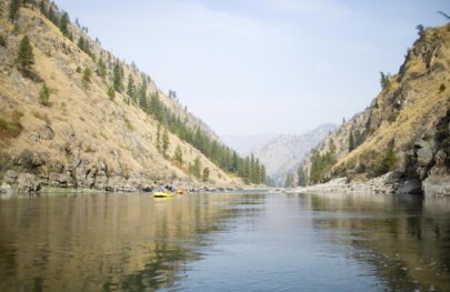 A yellow OARS raft floats on a calm stretch of the Main Salmon River in Idaho