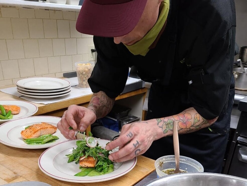 Chef Keenan McGrew prepares plates for service in a restaraunt kitchen.