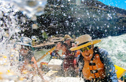 Happy guest in straw hat gets wet in whitewater Grand Canyon