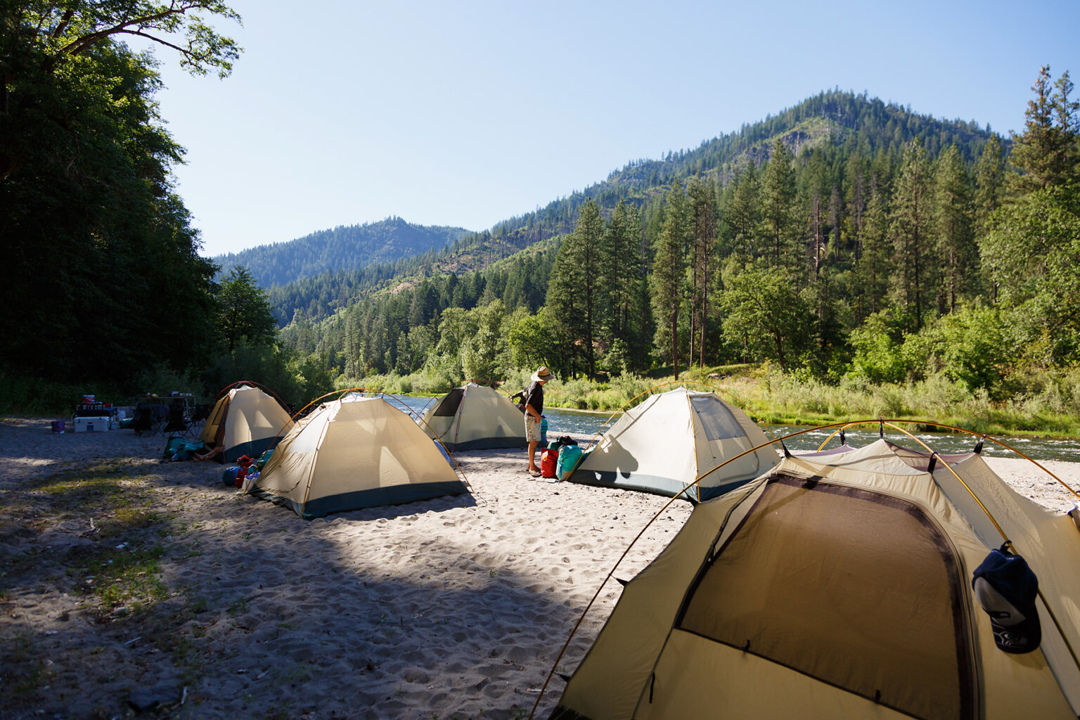 Several tents set up on a sandy beach at camp along the Lower Klamath River.
