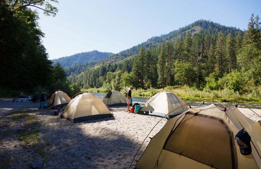 Several tents set up on a sandy beach at camp along the Lower Klamath River.