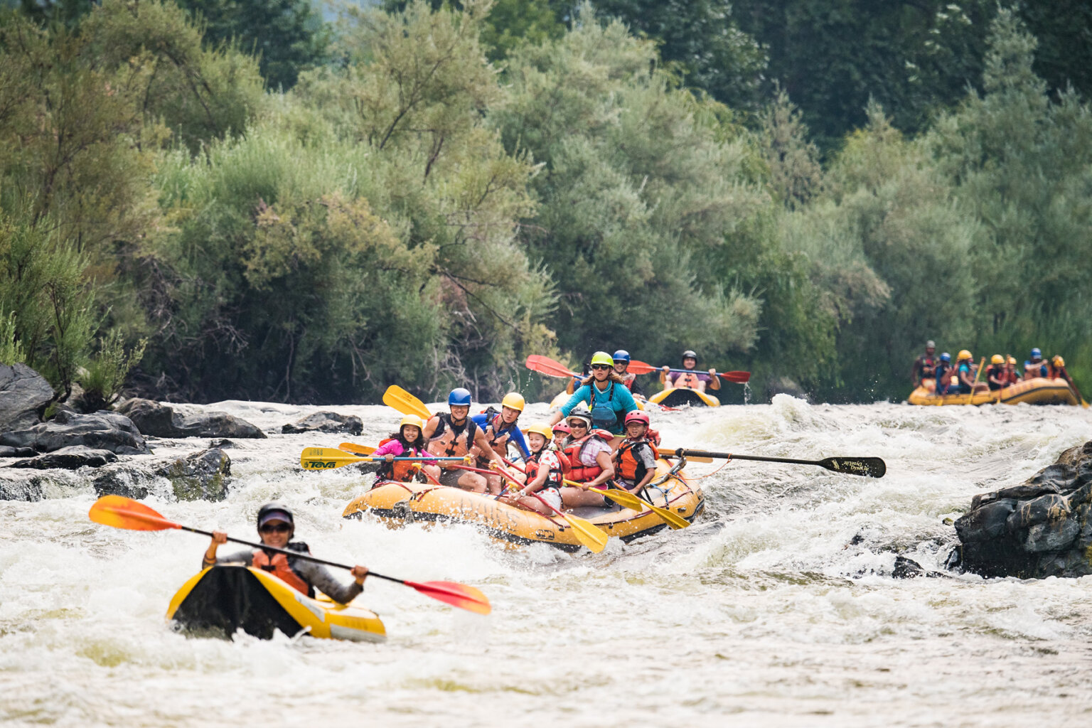 A kayaker leads a line of rafts and kayaks down a stretch of whitewater on the Lower Klamath River.