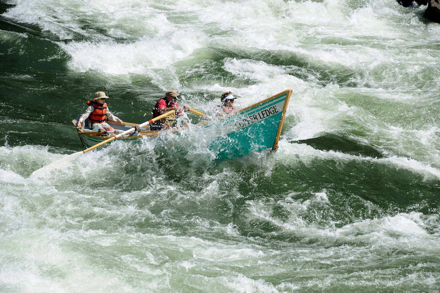Two guests and a guide in a dory as it plows through a rapid on the Main Salmon River.