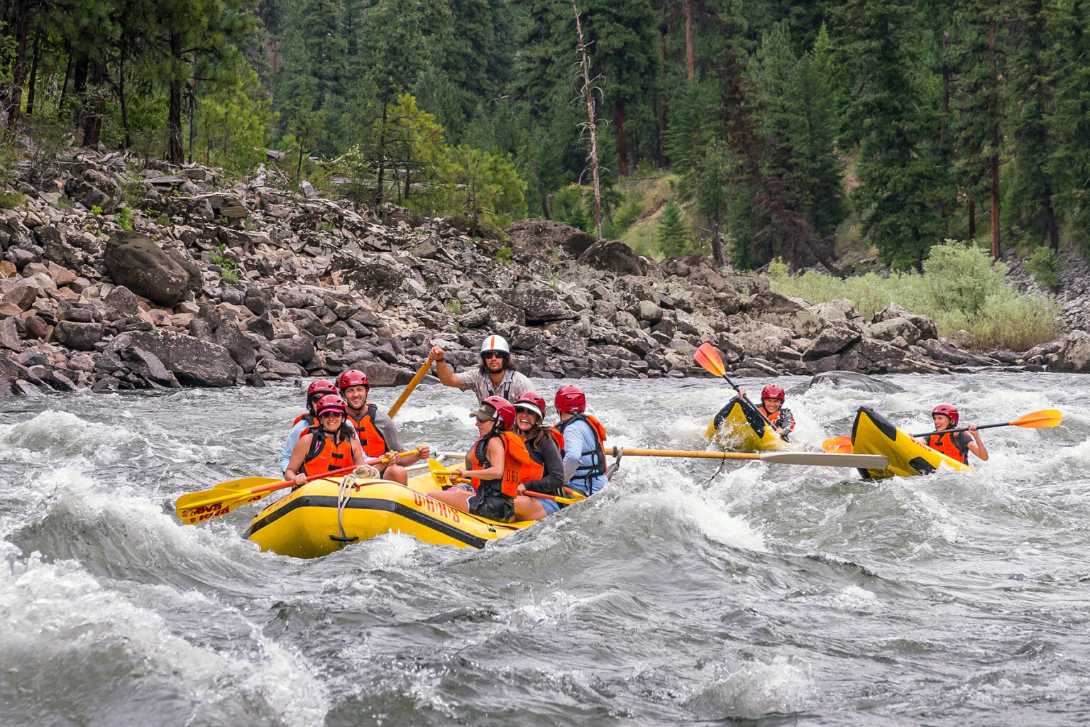 A paddle raft full of people is followed by two kayakers as they make their way through a stretch of whitewater on the Main Salmon River in Idaho.