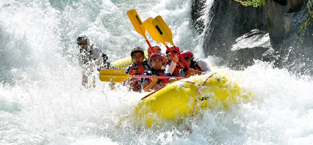 A yellow raft full of paddlers surrounded by frothy whitewater on the Middle Fork of the American River in California