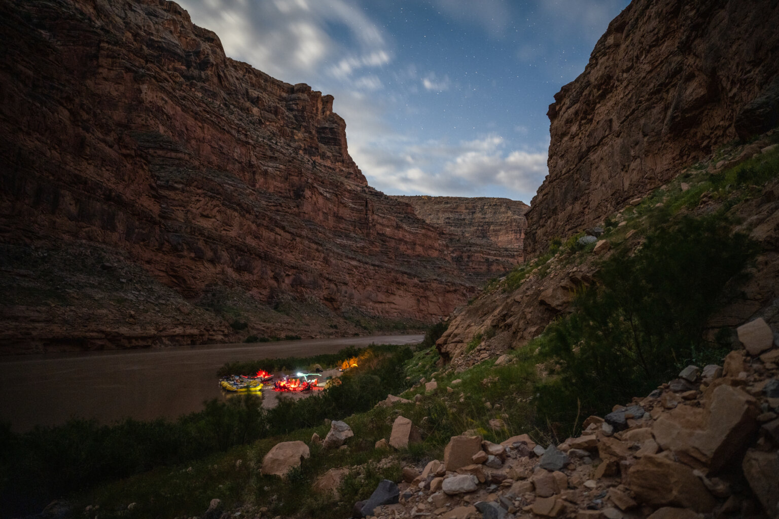 Twilight in Cataract Canyon with yellow rafts and camp in the distance on the shores of the Colorado River.
