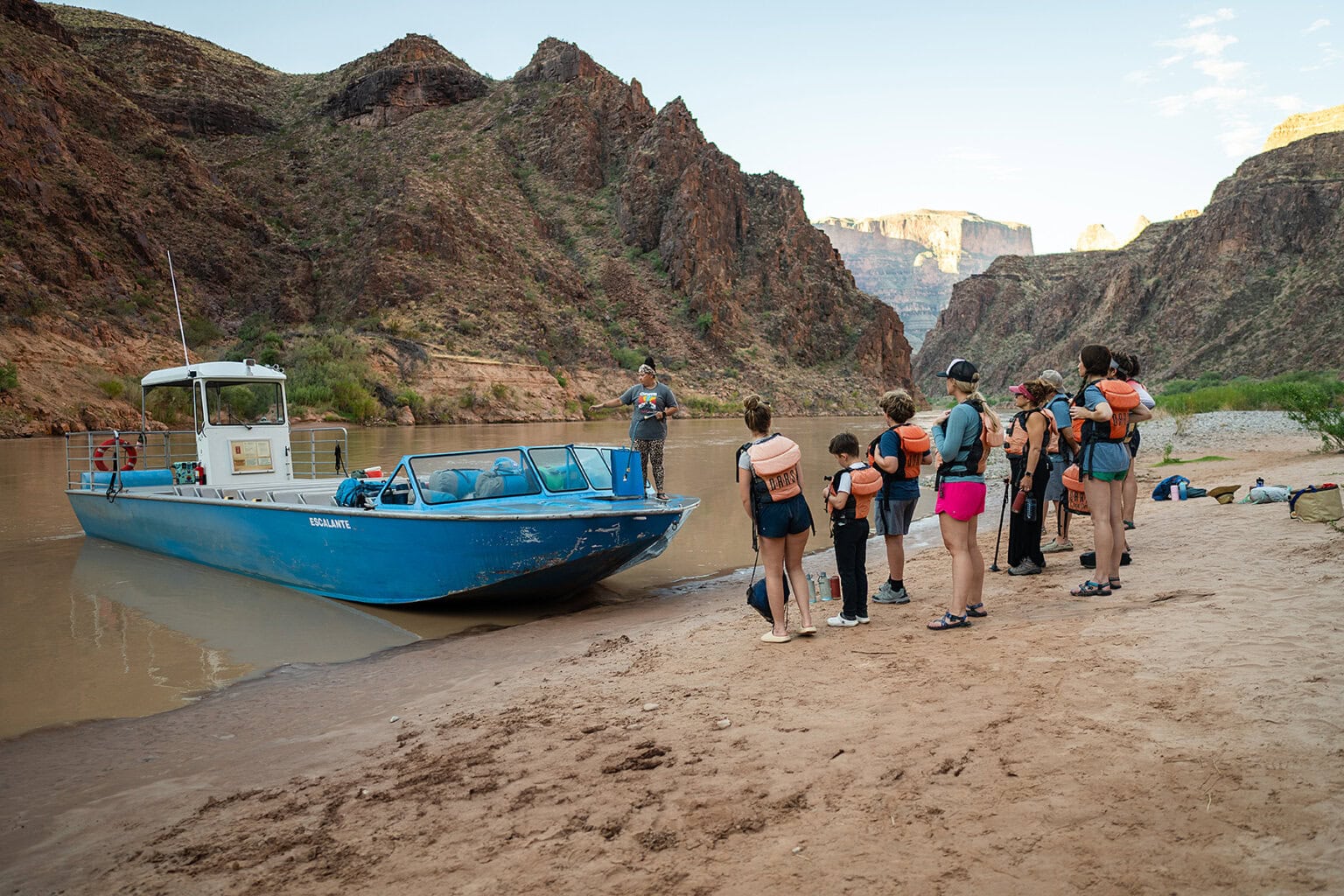 Guests wait to board a jet boat on a beach along the Colorado River in Grand Canyon