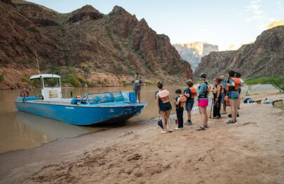 Guests wait to board a jet boat on a beach along the Colorado River in Grand Canyon