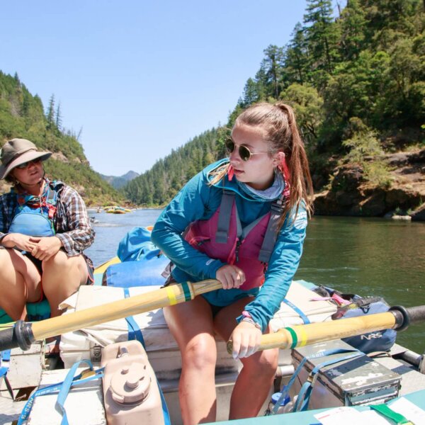A student rows an oar raft down the Rogue River as an instructor watches.