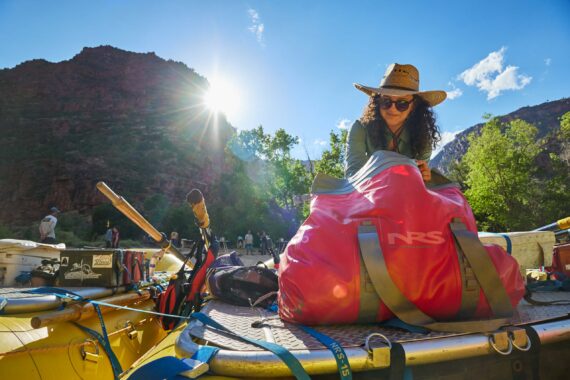 Woman in a hat packing a bag on a raft.