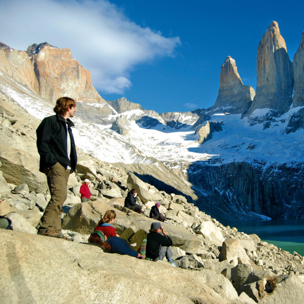 Guests sit on a rocky hillside during a hike and take in the view in Patagonia Chile.