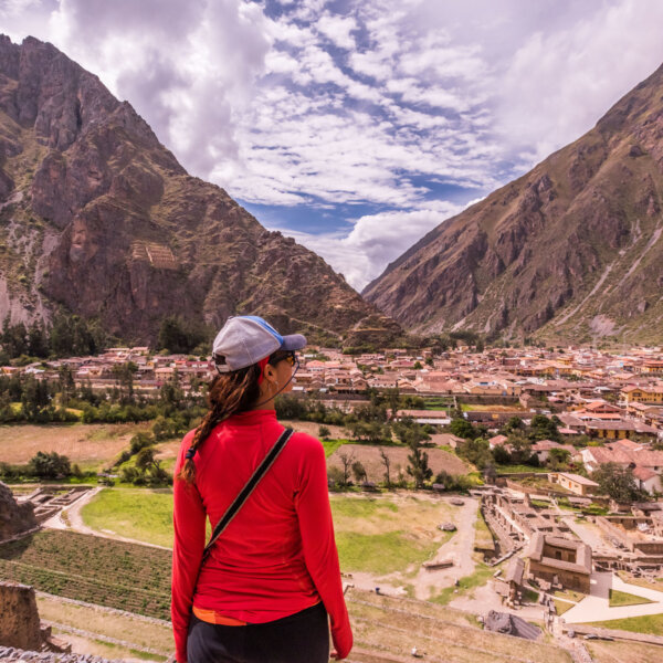 A woman stands and looks at Ollantaytambo below her in the Sacred Valley, Peru.