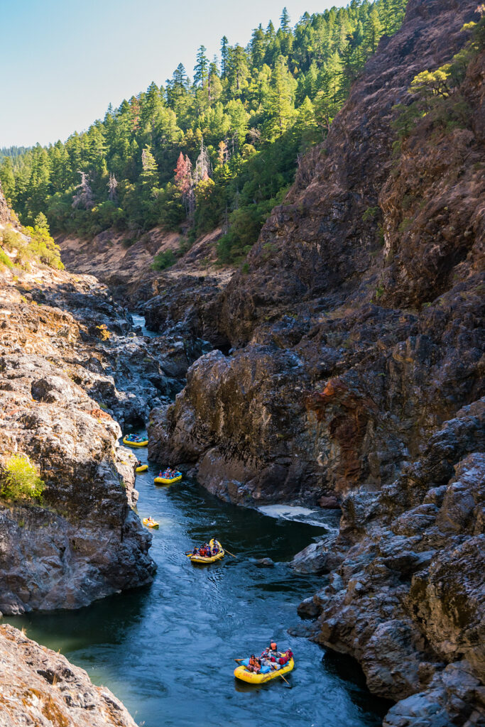 Rafts and inflatable kayaks maneuver through a rocky canyon on Oregon's Rogue River