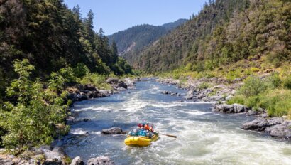 A yellow oar raft makes its way down the Rogue River in Oregon.