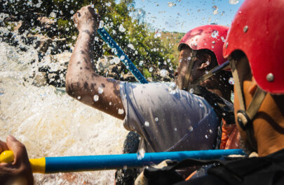 Close-up over the shoulder shot of two paddlers as they get splashed by water going through a rapid.