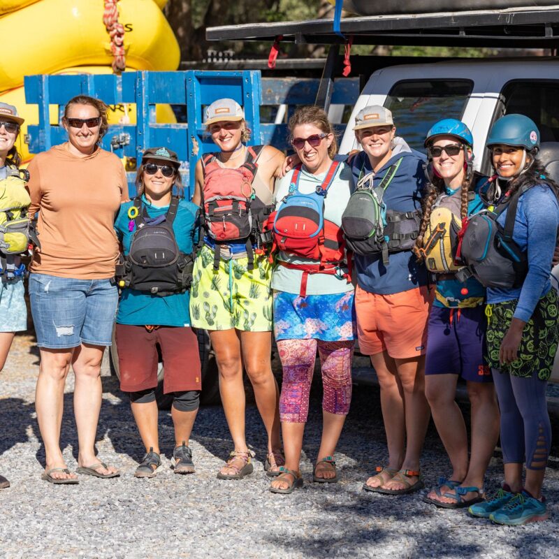A group of OARS women guides stands in front of a truck at the OARS American River Outpost