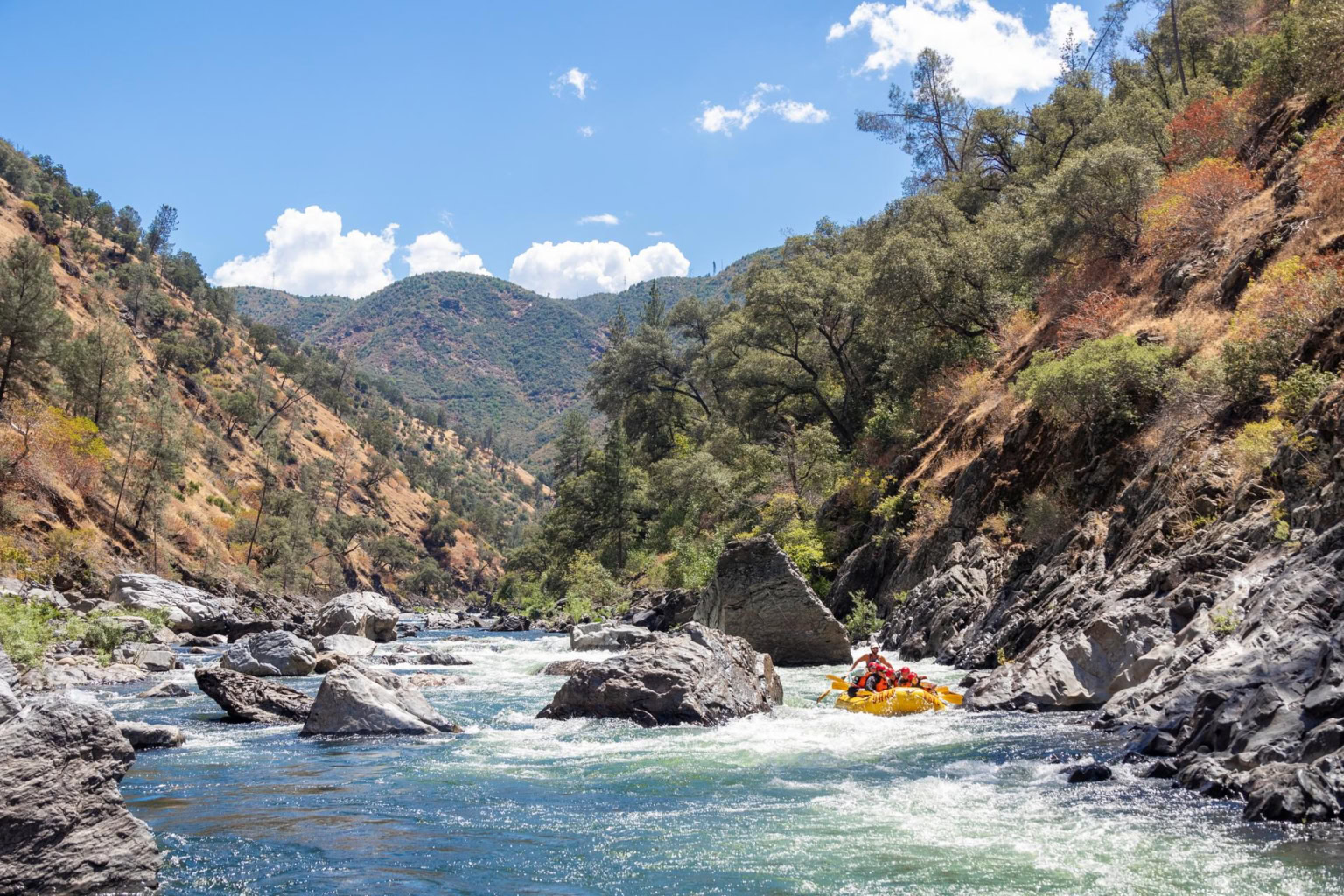 An OARS raft floating through a rocky section of the Wild & Scenic Tuolumne River
