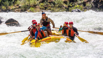 A yellow raft of paddlers surounded by frothy whitewater as they make their way through a rapid on the Tuolumne River in California