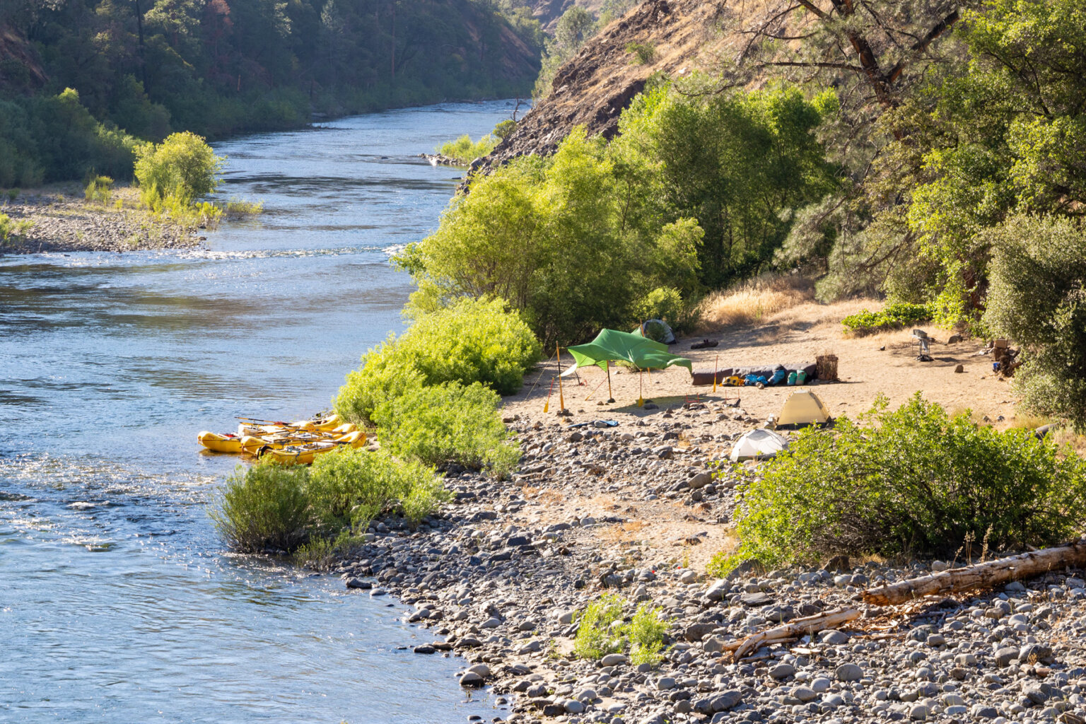 A shot of yellow rafts tied up at the shoreline of camp on the Tuolumne river.