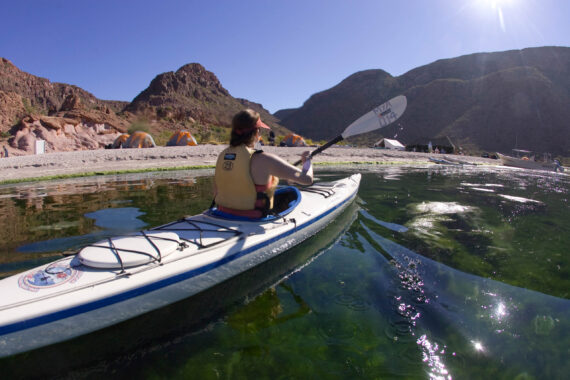 person rowing in a white kayak on a river.