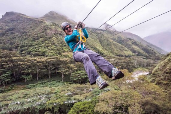 man riding a zipline off a mountain.
